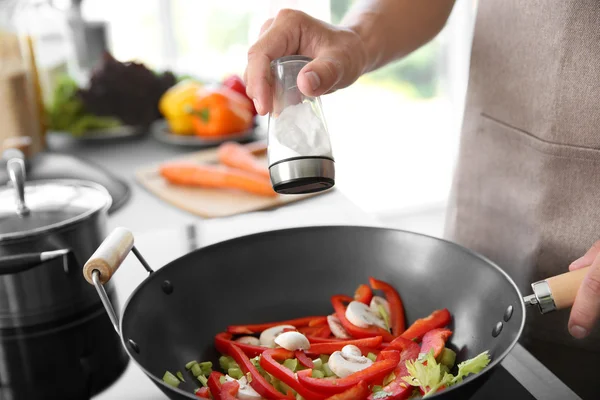 Mão masculina adicionando sal aos vegetais — Fotografia de Stock