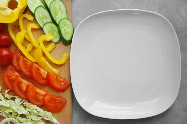 Plate and sliced vegetables — Stock Photo, Image