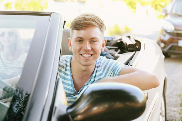 Happy young driver with friends in car