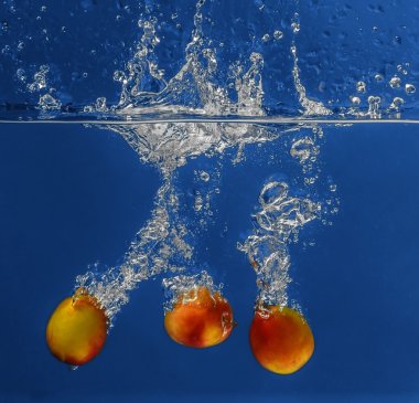 Su koyu arka plan üzerine düşen taze kayısı