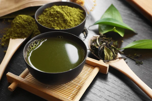 Tè matcha fresco e ciotola con polvere su supporto di legno — Foto Stock