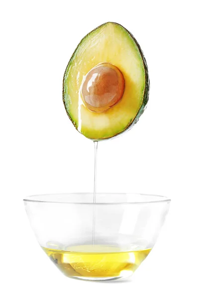 Aguacate y bowl con aceite de aguacate sobre fondo blanco . — Foto de Stock