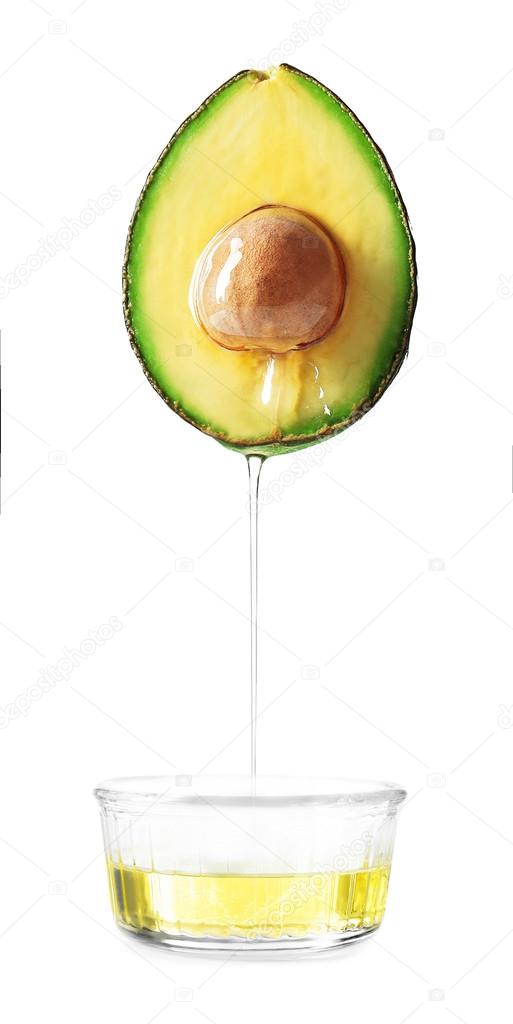 Avocado and bowl with avocado oil on white background.