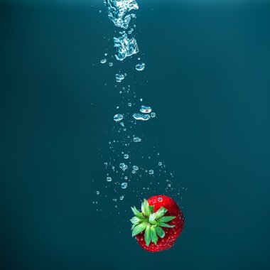 Su koyu arka plan üzerine düşen taze sulu çilek