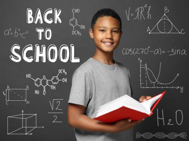 Sevimli çocuk gri arka plan üzerinde kitap okuma. Geri okul kavramı