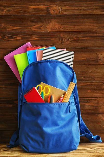 School rugzak met toebehoren op houten achtergrond — Stockfoto