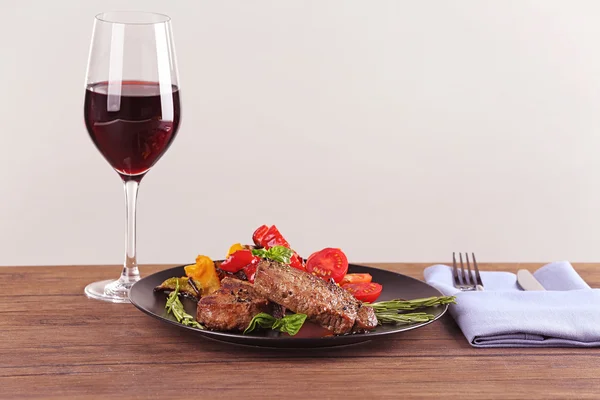 Delicious steak with vegetables and glass of wine on wooden table — Stock Photo, Image