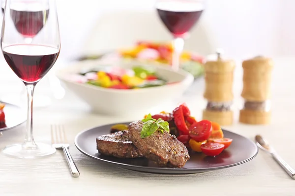 Tasty steak with fried vegetables on dinner table — Stock Photo, Image