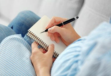 Not defterinde yazılı ve koltukta oturan hamile kadın
