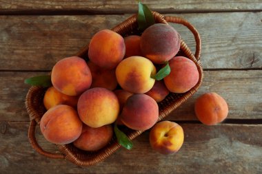 Tahta bir arka planda sepetteki taze şeftaliler.