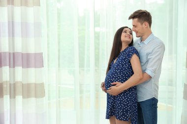 Genç hamile çift pencere karşı