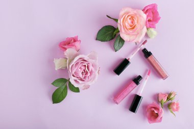 Dekoratif kozmetik ve çiçekler mor zemin üzerine
