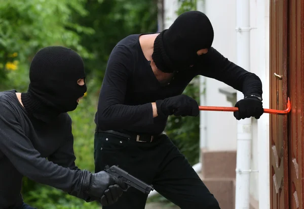 Armed thieves breaking a door — Stock Photo, Image