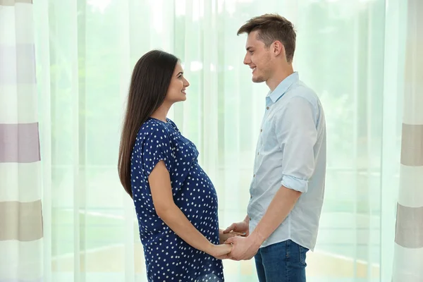 Zwangere paar tegen raam — Stockfoto