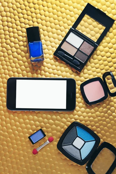 Cosmetici decorativi e smartphone su sfondo dorato — Foto Stock