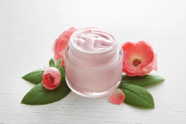 Gezicht crème en roze bloemen — Stockfoto