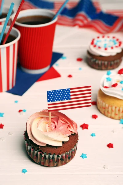 Läcker cupcake med flaggan dekoration och dryck på vit trä bakgrund — Stockfoto