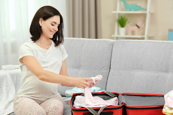 Raskaana oleva nainen valmistelee vauvan vaatteita — kuvapankkivalokuva