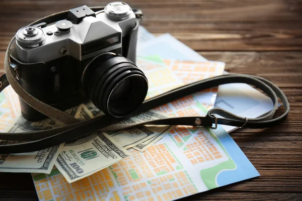 Vintage camera with map and cash on wooden table
