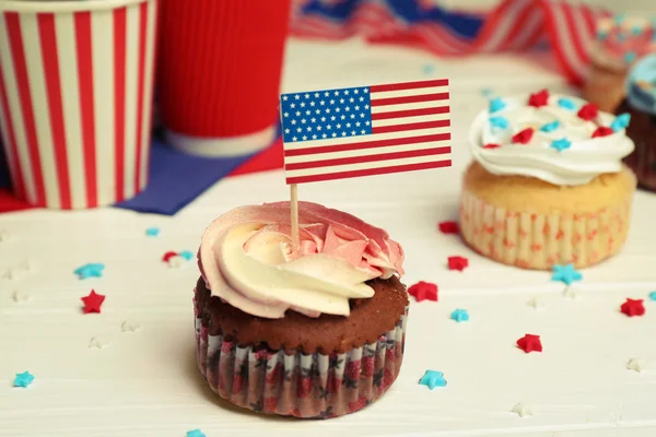 Delicioso cupcake con decoración de la bandera sobre fondo de madera blanca — Foto de Stock