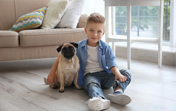 Pojke med mops hunden på golvet — Stockfoto