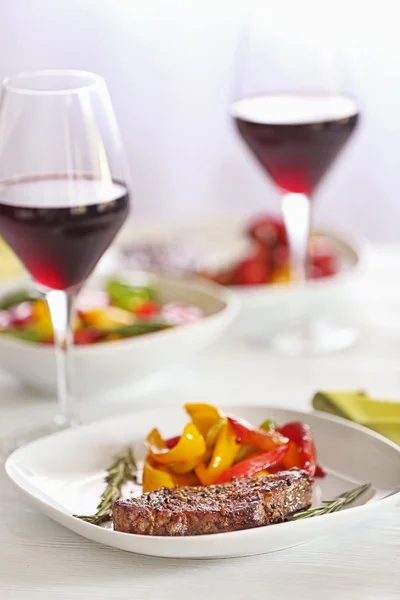 Tasty steak with fried vegetables on dinner table — Stock Photo, Image