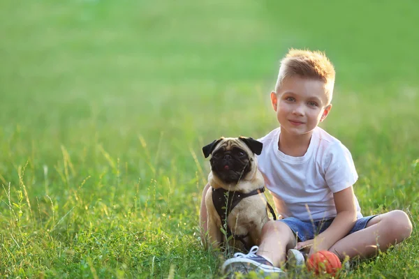 Çocuk ile pug köpek yeşil çimenlerin üzerinde — Stok fotoğraf