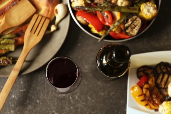 Verduras a la parrilla y copa de vino en la mesa servida — Foto de Stock