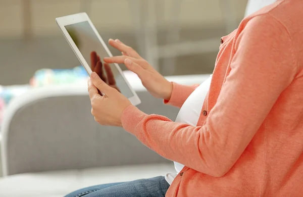 Femme enceinte avec tablette assise sur le canapé — Photo