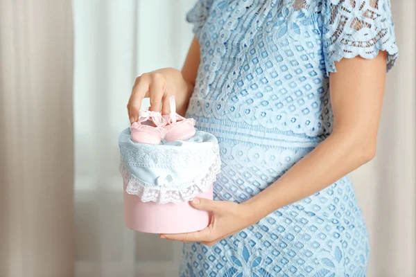 Pregnant woman holding pink box with baby booties — Stock Photo, Image