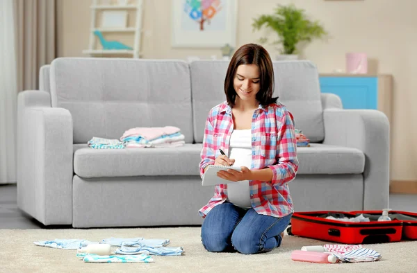 Těhotná žena dělat seznam balení — Stock fotografie