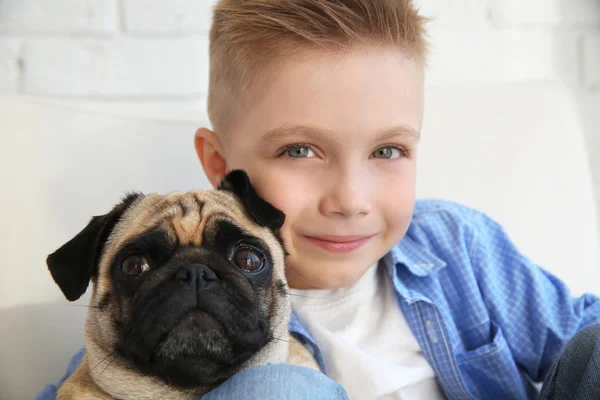 Мальчик с собакой-мопсом на диване — стоковое фото