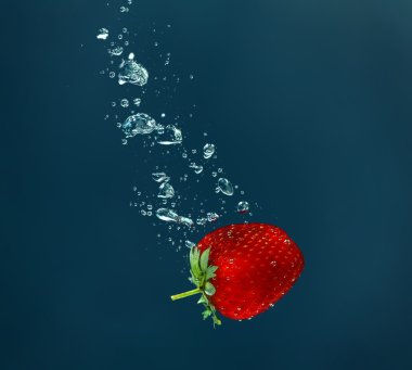 Su koyu arka plan üzerine düşen taze sulu çilek