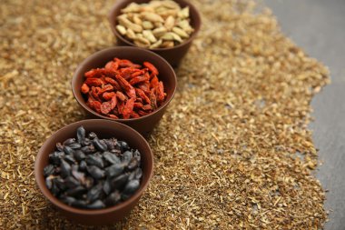 Kakule, kızamık ve goji meyveleri baharat arka plan üzerinde kase