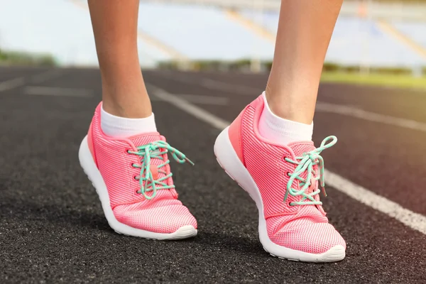 Donna che indossa scarpe da ginnastica rosa su uno stadio di corsa — Foto Stock