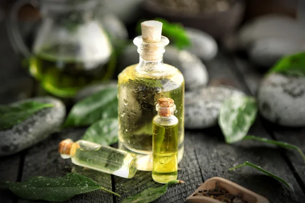 Composición del spa con aceite de té en botellas de vidrio y hojas frescas —  Fotos de Stock