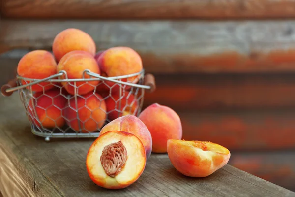 Fresh peaches in basket on wooden background — Stock Photo, Image