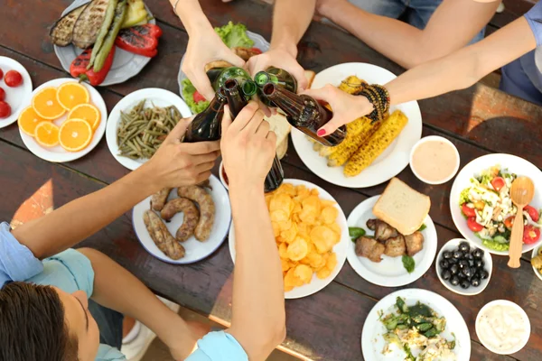 Vänner jublar med flaskor öl på picknick — Stockfoto