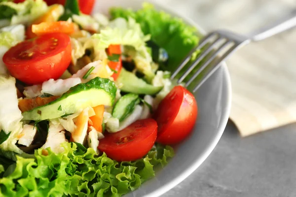 Teller mit frischem Salat auf grauem Tisch — Stockfoto