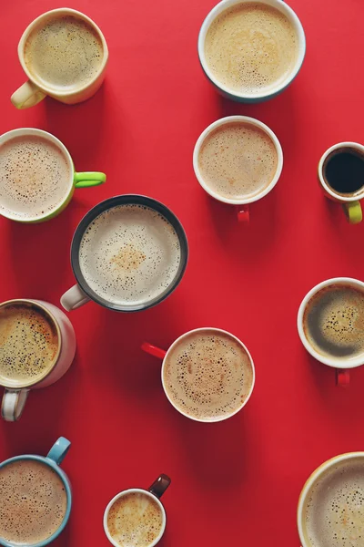 Šálků kávy na červeném pozadí, pohled shora — Stock fotografie