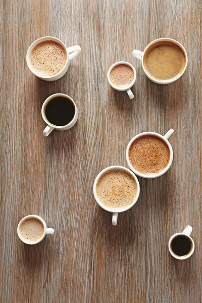 Kopjes koffie op houten achtergrond, bovenaanzicht — Stockfoto