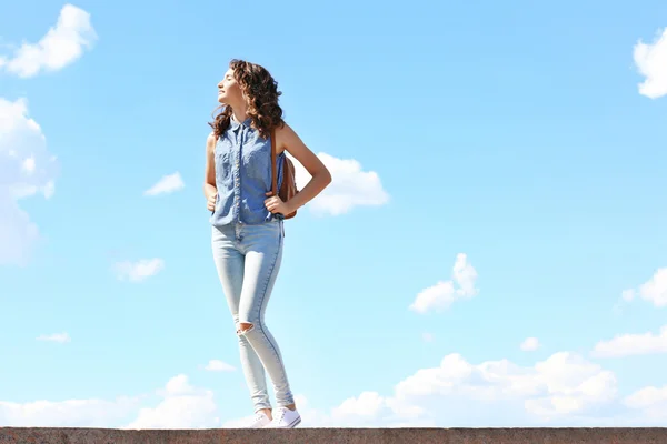 Beautiful young girl posing on blue sky background — Stock Photo, Image