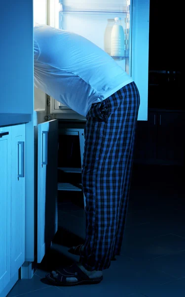 Человек забирает еду из холодильника — стоковое фото