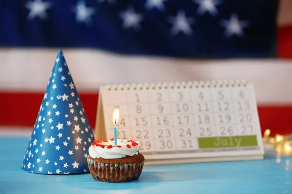 Cupcake con calendario sobre fondo borroso de la bandera americana. Concepto del día de la independencia — Foto de Stock