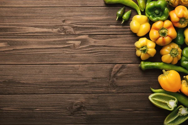 Čerstvé papriky na dřevěném stole — Stock fotografie