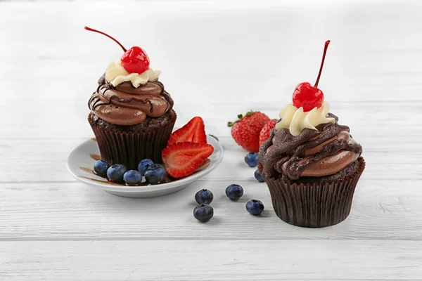 Deliciosos cupcakes de chocolate con bayas en la mesa blanca — Foto de Stock