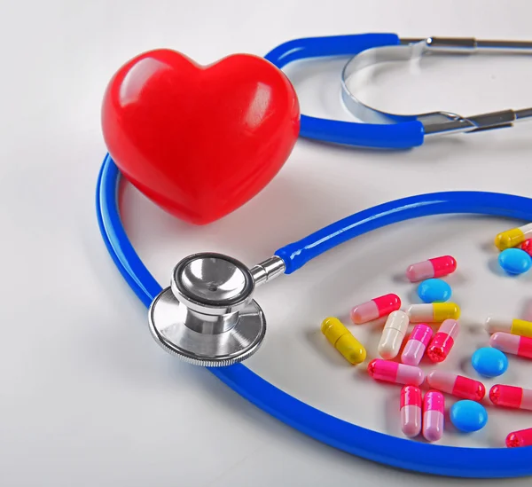 Stethoscope, pills and heart on white background, closeup — Stock Photo, Image