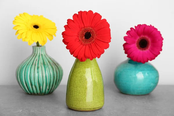 Vases with gerbera flowers on grey background — Stock fotografie