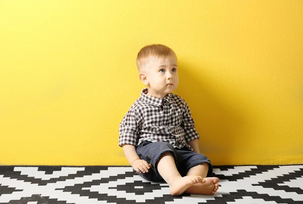 Menino Elegante Sentado Tapete Com Padrão Fundo Parede Amarelo — Fotografia de Stock