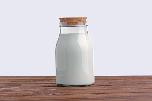 Mléko ve skleněné láhvi na dřevěný stůl — Stock fotografie